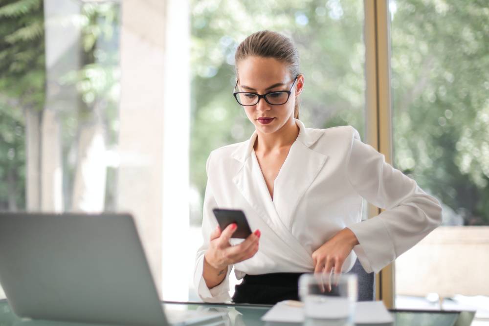 A woman in a business attire holding a mobile phone